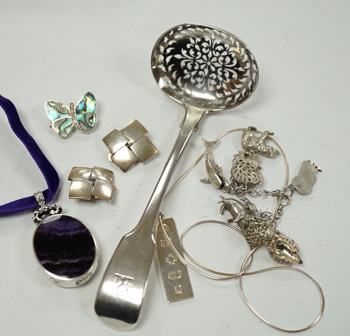 A modern silver mounted blue john pendant, by David Scott Walker, 54mm, together with other jewellery including silver ingot pendant, charm bracelet etc. and a George IV silver sifter spoon, William Eaton, London, 1829.